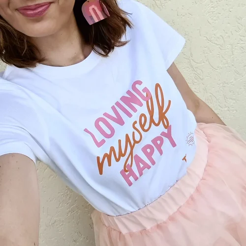 A model wearing a shirt with the text loving myself happy