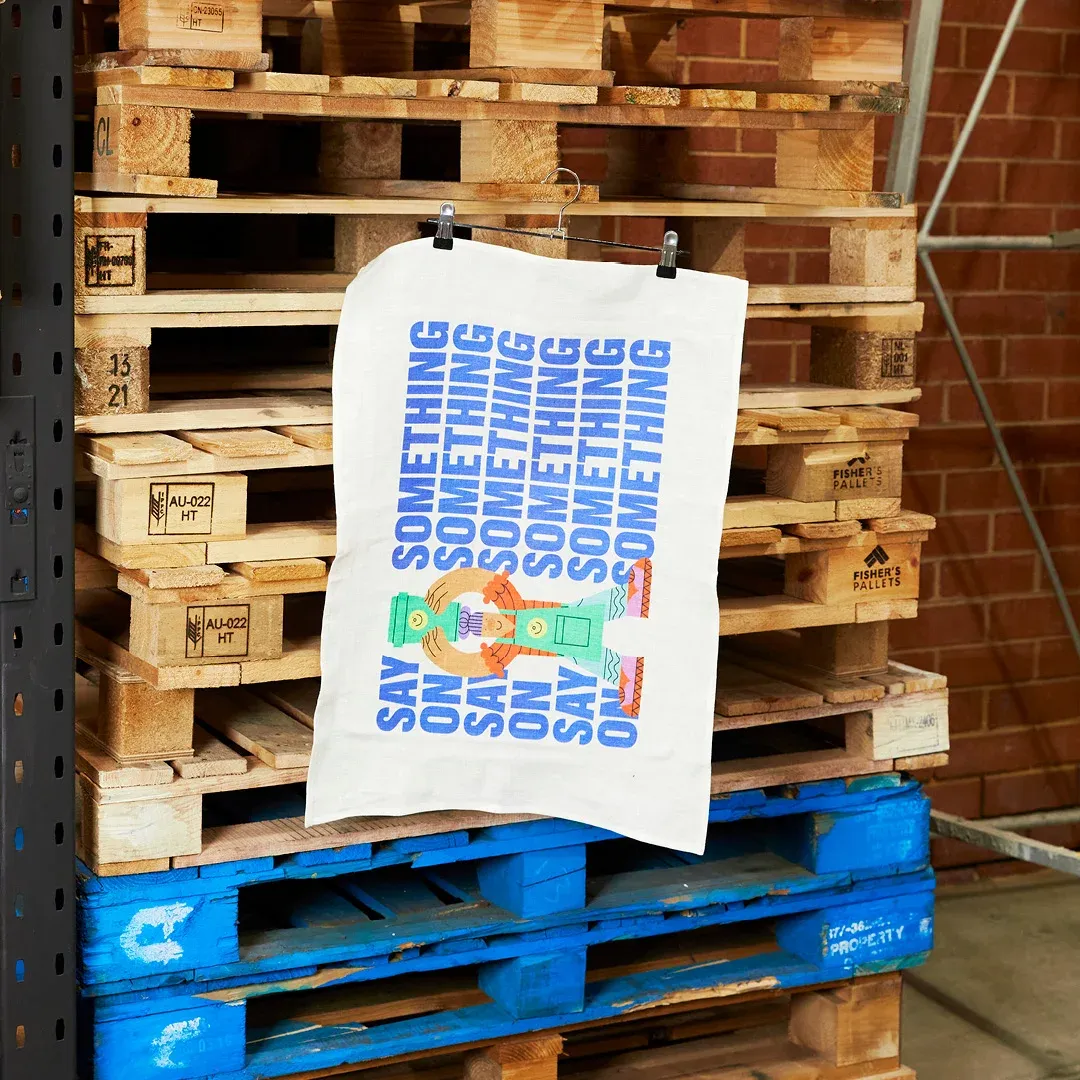 A screen printed tote bag hangs from a shipping crate awaiting to be sent Australia wide or internationally
