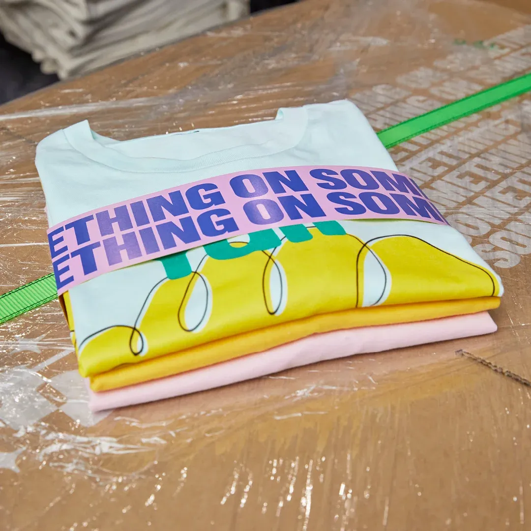 A stack of personalised t-shirts in a variety of colours wrapped and ready for delivery