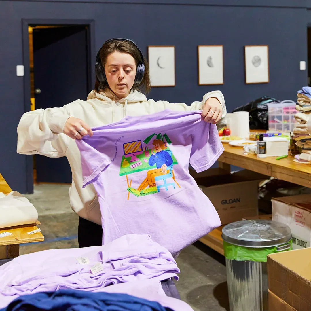 A person in The Print Bar's Melbourne location is folding a personalised t-shirt