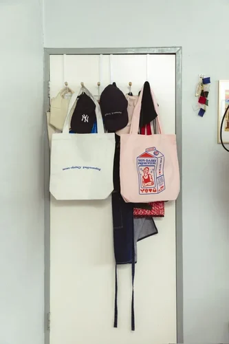 Two custom printed tote bags hang from the back of a door, they featured screen printed personalised designs