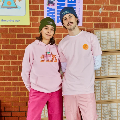 Two people in pink hoodies and sweatshirts stand near boxes at The Print Bar's Melbourne location