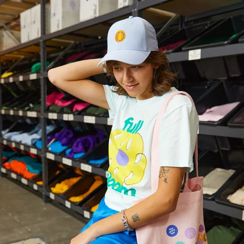 Person sits on a chair with a custom screen printed t-shirt and a personalised embroidered hat with a logo
