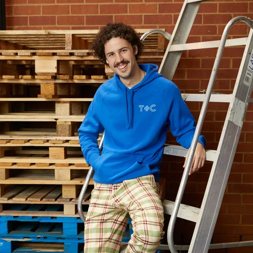 A person at The Print Bar Melbourne is leaning against a ladder wearing a custom blue jumper with a logo