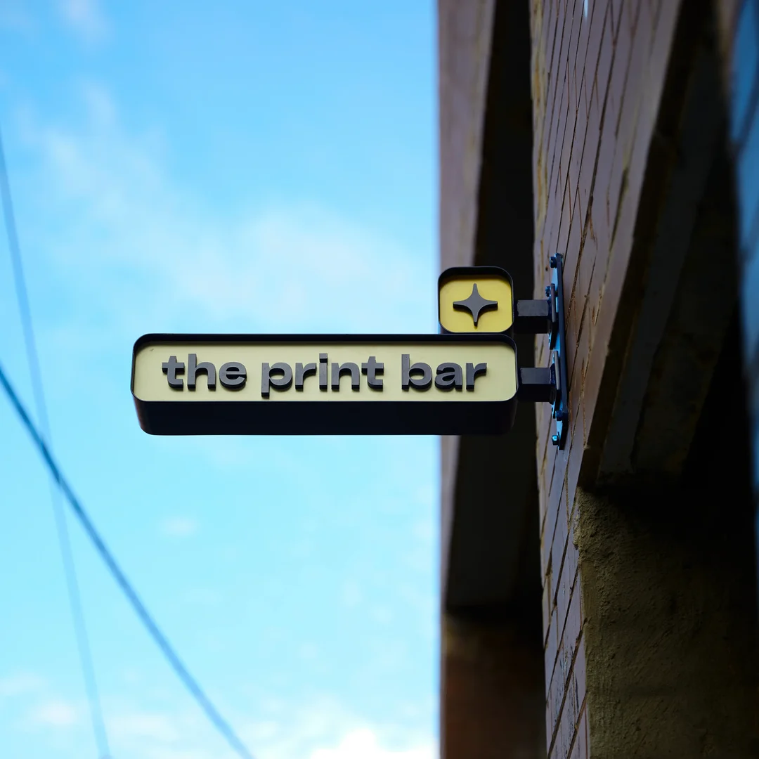 The Print Bar sign attached to the side wall of building where the Melbourne warehouse is located