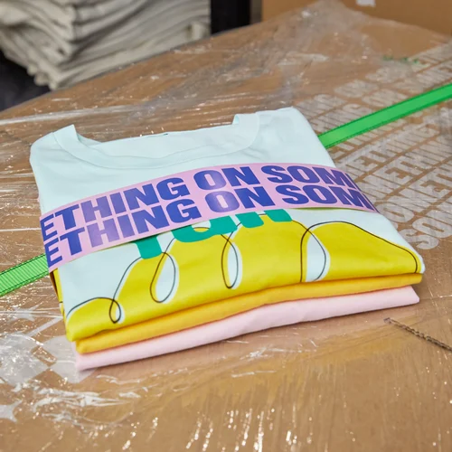 A stack of personalised t-shirts in a variety of colours wrapped and ready for delivery