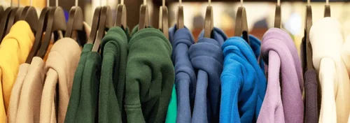 A line of hoodies are hanging up on clothing rack