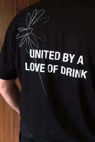 The back of a shirt reads 'UNITED BY A LOVE OF DRINK' with a flower outline print
