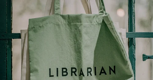 A green Tote Bag hanging reads 'LIBRARIAN'